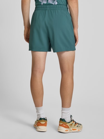 Männermodel trägt Regular Fit Sportshorts mit Logo-Print Modell 'TAD ESSENTIALS' von PUMA in Grün, Herren Sportshorts, Ganzkörperansicht Rückansicht.