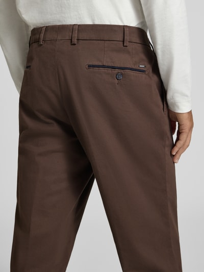 Männermodel trägt braune Regular Fit Chino aus Baumwoll-Mix Modell 'PEAKER' von Hiltl, glatte Textur, Herren Weite Hose, Nahaufnahme Rückansicht.