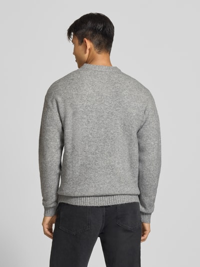 Männermodel trägt grauen Strickpullover mit Rundhalsausschnitt Modell 'SOHO OLLIE' von JACK & JONES, Material-Mix, Ganzkörperansicht Rückansicht.