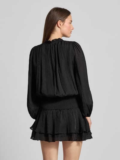 Vrouwenmodel draagt Cocktailjurk im Stufen-Look Modell 'Bari' van Neo Noir in zwarte chiffon, getailleerd model, mini-jurk, druppelvormige hals, vetersluiting, laagjeslook, ruglengte 88 cm, borstwijdte 37 cm, mouwlengte 68 cm, textuur met lichte glans. Ganzkörperansicht Rückansicht.