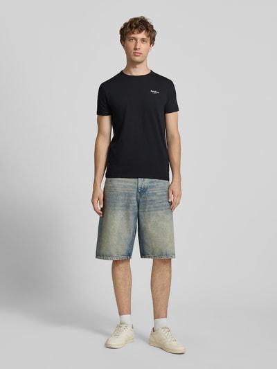 Männermodel trägt Slim Fit T-Shirt aus Baumwoll-Mix Modell 'ORIGINAL BASIC 3' von Pepe Jeans in Schwarz, melange Optik, Ganzkörperansicht von vorne.