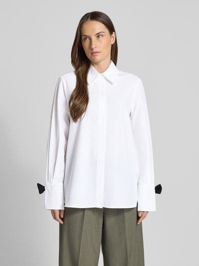 Frauenmodel trägt Hemdbluse mit Knopfleiste von Marella aus reiner Baumwolle, lockerer Schnitt, weiß, große Manschetten, Ganzkörperansicht von vorne.