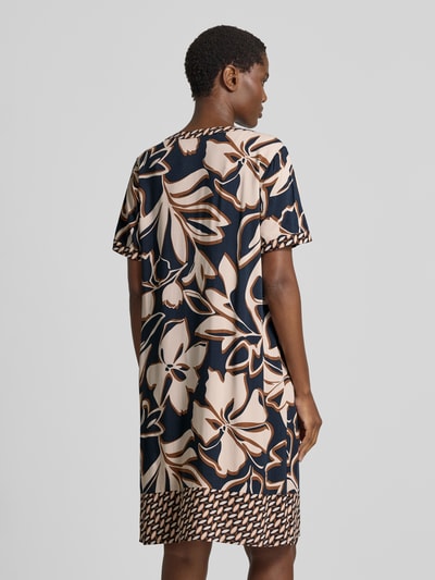 Frauenmodel trägt A-Linien Freizeitkleid aus reiner Viskose von Betty Barclay mit floralem Muster in Beige und Schwarz, Ganzkörperansicht Rückansicht.