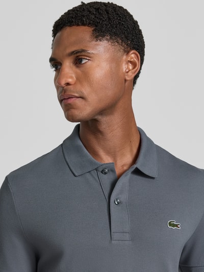 Männermodel trägt Slim Fit Poloshirt aus reiner Baumwolle von Lacoste in Grau mit strukturierter Oberfläche, Nahaufnahme Oberkörper. Herren Poloshirt von Lacoste.