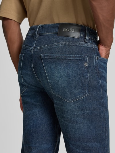Männermodel trägt Straight Fit Jeans aus Baumwoll-Mix Modell 'C-Ogden' von BOSS in dunklem Blau mit sichtbarer Textur, Nahaufnahme Rückansicht, Herren Straight Fit Jeans von BOSS