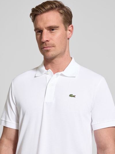 Männermodel trägt Regular Fit Poloshirt aus Baumwoll-Mix von Lacoste, Optik: Unifarben, Logo-Detail, Nahaufnahme Oberkörper.