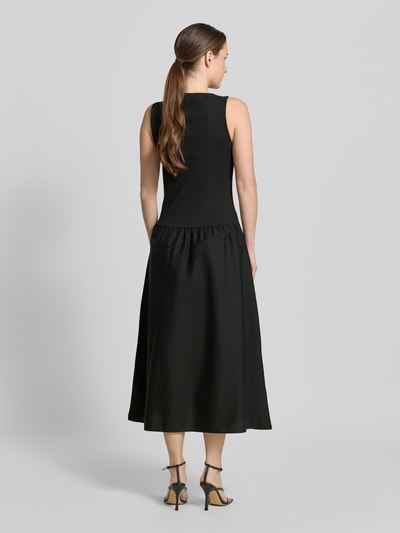Frauenmodel trägt Midikleid mit U-Boot-Ausschnitt Modell 'VALVIN' von Mango aus schwarzem Baumwoll-Mix mit Stretch-Anteil, Taillierter Schnitt, breite Träger, glatte Textur, Rückenlänge bei Größe S 128 cm, Brustweite 40 cm, Ganzkörperansicht Rückansicht.
