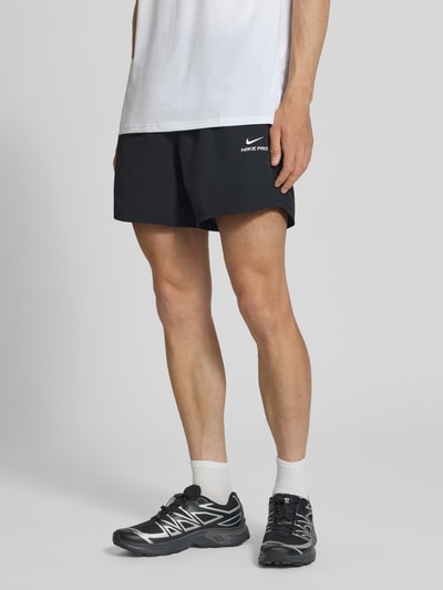 Männermodel trägt Shorts mit Logo und elastischem Bund von NIKE TRAINING, Schwarz, Regular Fit, Material-Mix mit Stretch, Nahaufnahme Oberkörper.