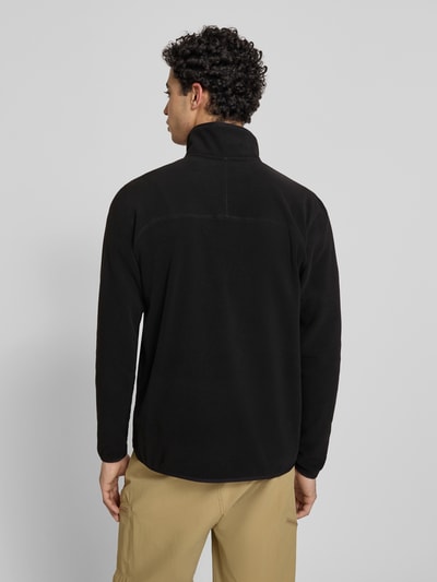 Männermodel trägt Fleecepullover mit Reißverschluss Modell 'GLACIER' von The North Face in Schwarz, Label-Stitching, Regular-Fit, Stehkragen, Rückenlänge 70 cm, Ärmellänge 67 cm, Ganzkörperansicht Rückansicht.