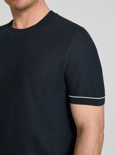 Männermodel trägt Regular Fit T-Shirt aus Strick Modell 'H-NALON' von BOSS in Strickoptik, Baumwoll-Mix, Nahaufnahme Oberkörper.