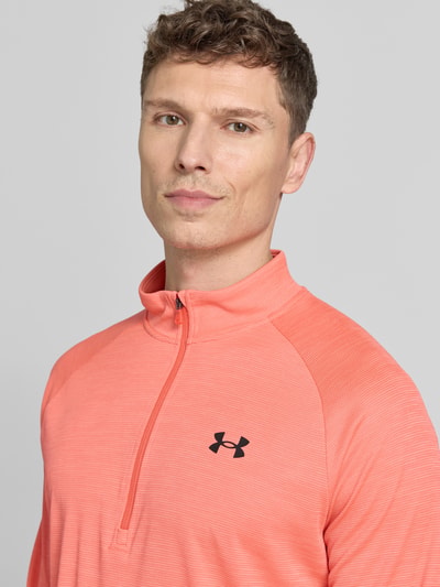 Männermodel trägt Sweatshirt mit kurzem Reißverschluss und Logo-Print von Under Armour in Koralle, strukturierte Oberfläche, Nahaufnahme Oberkörper