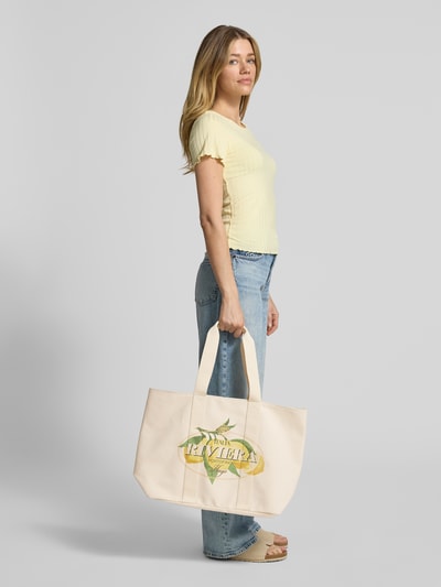 Frauenmodel trägt Strandtasche aus reiner Baumwolle Modell 'BECKY CPR' von HUGO, unifarben, Motiv-Print, hellbeige, Ganzkörperansicht von vorne.