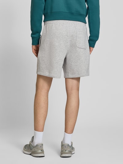 Männermodel trägt Relaxed Fit Shorts mit Logo-Stitching von New Balance, hellgrauer Baumwoll-Mix, elastischer Bund, Ganzkörperansicht Rückansicht