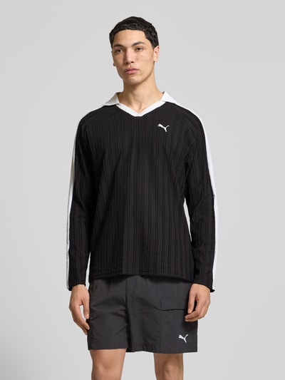Männermodel trägt Relaxed Fit Polo-Longsleeve mit Label-Stitching von PUMA PERFORMANCE in Schwarz mit weißen Details, Ganzkörperansicht von vorne.