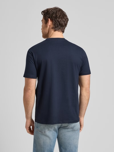 Męski model nosi T-Shirt mit Rundhalsausschnitt und Label-Stitching od Guess, czysta bawełna, krój regular fit, model 'FLAGS AND CORD', granatowy, tekstura gładka, długość tyłu w rozmiarze M: 70 cm, całopostaciowy widok z tyłu.