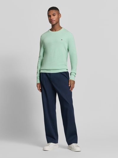 Männermodel trägt Regular Fit Strickpullover aus reiner Baumwolle von Tommy Hilfiger, Optik: Unifarben, Strickoptik, Logo-Detail, Rundhals, Langarm, gerippte Abschlüsse, Material: Strick, Ganzkörperansicht von vorne.