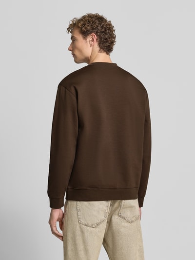 Mannenmodel draagt slim fit pullover uit pure katoen 'TOM' van Selected, effen bruin, grof geweven textuur, hele lichaam achteraanzicht. Heren sweatshirt
