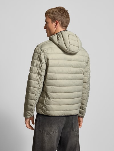 Männermodel draagt Gewatteerd jack met capuchon en logoprint van CHAMPION in regular fit, lichtgrijs, steekzakken, ritssluiting, Ganzkörperansicht Rückansicht. Ruglengte 71 cm, schouderbreedte 51 cm, borstwijdte 61 cm, mouwlengte 69 cm, maat M.