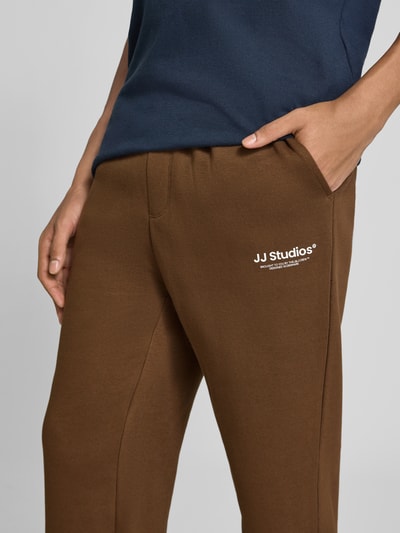 Männermodel trägt Straight Fit Sweatpants aus Baumwoll-Mix Modell 'Kane' von JACK & JONES, Logo-Detail, Nahaufnahme Oberkörper, KI-modifiziertes Bild.