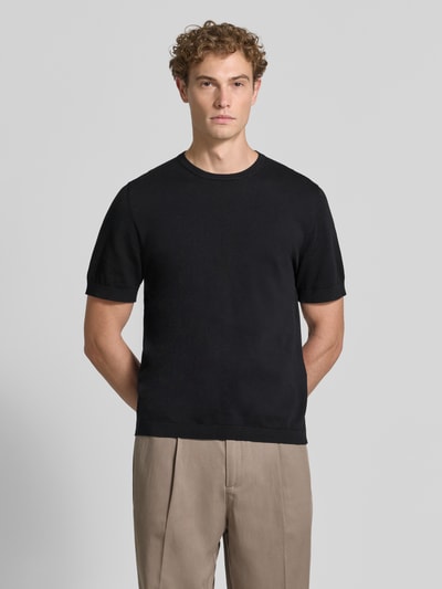 Męski model nosi Regular Fit T-Shirt aus reiner Baumwolle Modell 'TORINO' od SELECTED HOMME, jednokolorowy, krótki rękaw, okrągły dekolt, prążkowane wykończenia, materiał: bawełna, kolor czarny, gładka faktura, całopostaciowy widok z przodu.