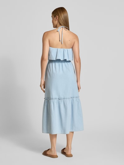 Frauenmodel trägt Jeanskleid mit Neckholder Modell 'LUMIRA' von Drykorn aus Reine Baumwolle, Taillierter Schnitt, Midikleid, Rückenlänge 110 cm, Brustweite 33 cm, hellblau, weich fallender Stoff, Volant-Ausschnitt, Ganzkörperansicht Rückansicht.