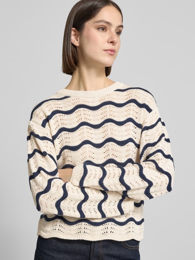 Frauenmodel trägt Regular Fit Pullover in Strick-Optik Modell 'Wave' von Vila aus Reine Baumwolle mit Lochmuster und Rundhalsausschnitt, cremefarbene Grundfarbe mit dunkelblauen Wellenlinien, Damen Pullover mit taillierter Passform, Rückenlänge bei Größe S: 54 cm, Ärmellänge 63 cm, Ganzkörperansicht von vorne.