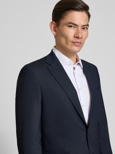 Männermodel trägt Slim Fit Anzug mit Schurwoll-Anteil Modell 'HUGE' von BOSS in Dunkelblau mit feinem Allover-Muster, Nahaufnahme Oberkörper.