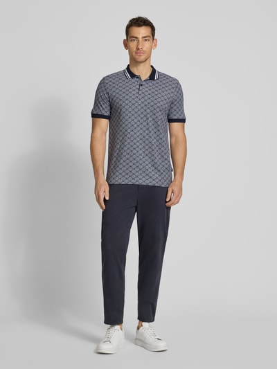 Męski model nosi Regular Fit Poloshirt mit Logo-Muster Modell 'Jessino' von JOOP! Collection z czystej bawełny, krój regular fit, zapięcie na guziki, długość tyłu w rozmiarze M: 69 cm, widok całej sylwetki z przodu.