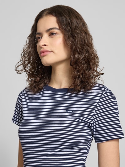 Modelka kobieca nosi Slim Fit T-Shirt aus reiner Baumwolle od Levi's®, granatowo-białe paski, label patch, okrągły dekolt, krótki rękaw, bawełna, krój slim fit, zbliżenie na górną część ciała