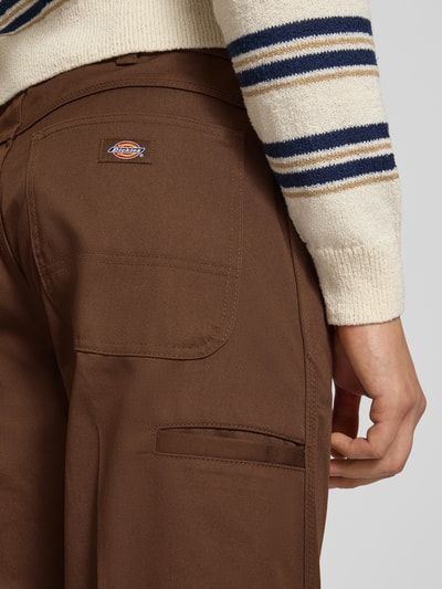 Männermodel trägt Loose Straight Fit Hose mit Bügelfalten von Dickies in Braun, Baumwoll-Mix, Detailaufnahme Rückansicht.