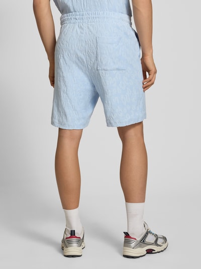 Męski model nosi Regular Fit Shorts aus Frottee od HUGO, jasnoniebieska frotte, tekstura, kieszenie, logo; widok całej sylwetki z tyłu.