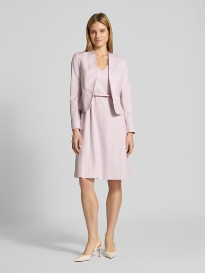 Frauenmodel trägt Knielanges Kleid mit Gürtel von Christian Berg Woman Selection, zartrosafarbener Material-Mix mit Viskose-Anteil, A-Linie, fein strukturiert, V-Ausschnitt, Knielänge, kombiniert mit kurzem Blazer, Ganzkörperansicht von vorne.