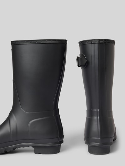 Produktfoto, Stiefel mit Label-Patch von Hunter aus schwarzem Gummi, abgerundete Passform, Zier-Applikation mit Dornschließe, strukturierte Sohle, Blockabsatz, Absatzhöhe 3 cm, Schafthöhe 26 cm, Schaftweite 15 cm, matte Textur