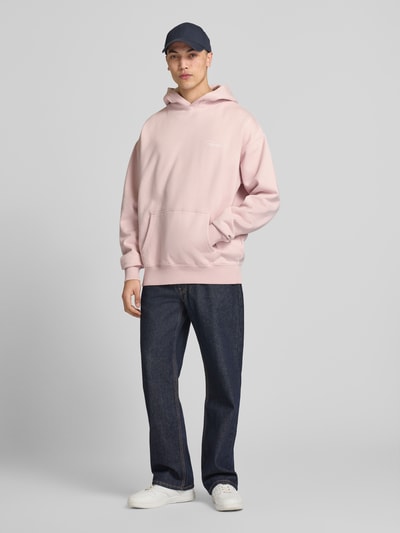 Männermodel trägt Oversized Hoodie mit Känguru-Tasche Modell 'Pike' von Pegador aus Baumwoll-Mix, Label-Print, Ganzkörperansicht von vorne.