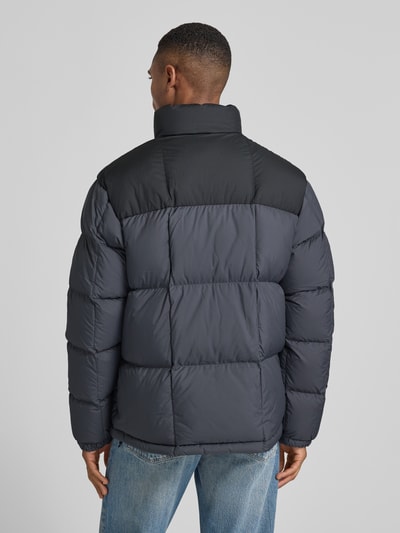 Męski model nosi Regular Fit Daunenjacke mit Zweiwege-Reißverschluss Modell 'GORHAM' od Polo Ralph Lauren w odcieniach szaro-czarnych, jednolita powierzchnia, prosty krój, dwutonowa kolorystyka, widok całej sylwetki od tyłu.