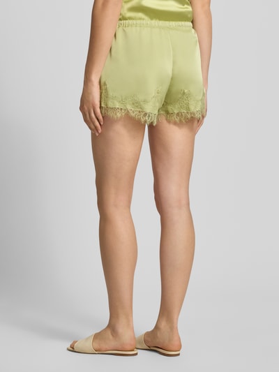 Frauenmodel trägt Shorts aus Satin mit Spitzenbesatz von Gina Tricot in Hellgrün, Regular-Fit, elastischer Bund, Tunnelzug, Ganzkörperansicht Rückansicht.
