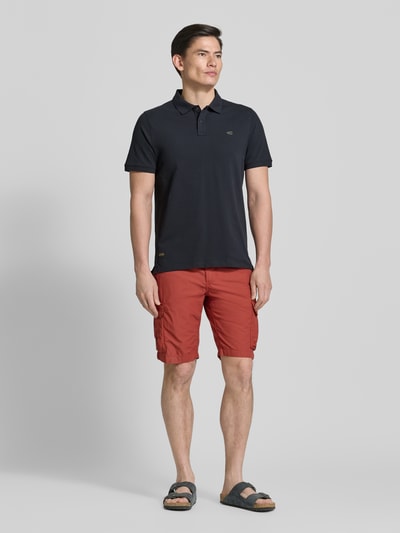 Mannenmodel draagt Regular Fit Poloshirt in unifarbenem Design van camel active, katoen-elastaan mix, knoopsluiting, logo, ruglengte 70 cm, uni zwart, volledige lichaamsvoorzijde.