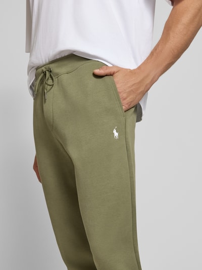 Männermodel trägt Regular Fit Sweathose aus Baumwoll-Mix von Polo Ralph Lauren in Olivgrün mit Kordelzug, Nahaufnahme Oberkörper. Herren Sweathose von Polo Ralph Lauren