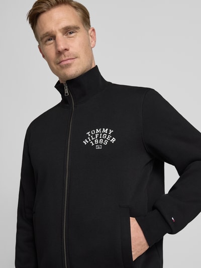 Mannenmodel draagt Regular Fit Sweatjacke uit katoenmix van Tommy Hilfiger, effen kleuren, labelprint, opstaande kraag, steekzakken, sweatmateriaal. Nahaufnahme Oberkörper.