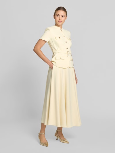 Frauenmodel trägt Maxikleid mit Stehkragen von Self-Portrait in Creme, taillierte Passform, abnehmbarer Taillengürtel, Pattentaschen, kurzärmelig, glatter Stoff, Gesamtlänge 132 cm bei Größe 36, Brustweite 45 cm, Taillenweite 39 cm, Ärmellänge 21 cm, Ganzkörperansicht von vorne.