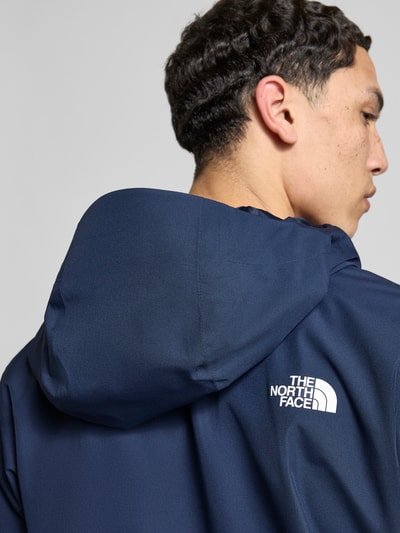 Mężczyznamodel nosi Jacke mit Kapuze od The North Face, krój regular fit, granatowa, logo na plecach, detal kaptura, zbliżenie na plecy.