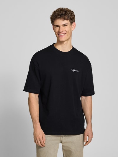 Männermodel trägt Oversized Herren T-Shirt von Pegador in Schwarz, Reine Baumwolle, Logo-Stitching, Rundhalsausschnitt, 1/2-Arm, Modell 'Signar', Rückenlänge bei Größe M 70 cm, Ganzkörperansicht von vorne.