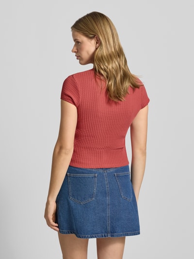 Frauenmodel trägt Damen T-Shirt Slim Fit Modell 'AJOUR' mit durchgängiger Knopfleiste von REVIEW, Reine Baumwolle, Kurzärmelig, Rundhalsausschnitt, Rückenlänge bei Größe S 49 cm, strukturierte Oberfläche, Farbe Altrosa, kombiniert mit einem blauen Jeansrock, Ganzkörperansicht Rückansicht.