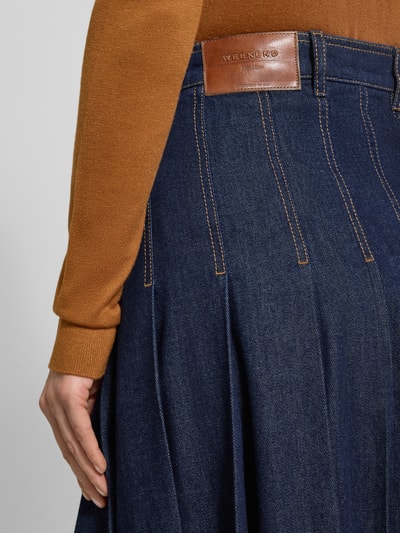 Kobiece model nosi rozkloszowaną spódnicę jeansową z czystej bawełny Ausgestellter Jeansrock aus reiner Baumwolle Modell 'OVALE' od Weekend Max Mara w kolorze granatowego denimu z kontrastowymi przeszyciami, label patch i szlufkami; detaliczny widok z tyłu.