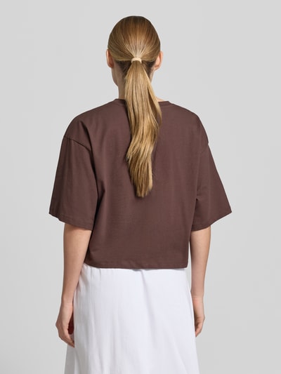 Frauenmodel trägt Cropped Boxy Fit T-Shirt mit Rundhalsausschnitt von Smith and Soul aus Reiner Baumwolle in Braun mit sichtbarem Stitching, Rückenlänge bei Größe S: 49 cm, Ganzkörperansicht Rückansicht.