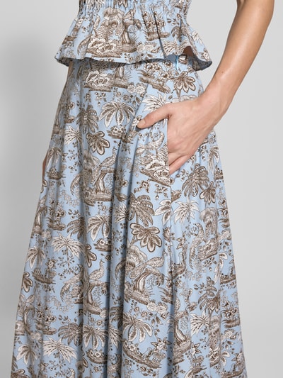 Vrouwenmodel draagt Midirock met naadritssluiting model 'Axel' van Staud, lichtblauwe florale allover-print, detailopname heup.