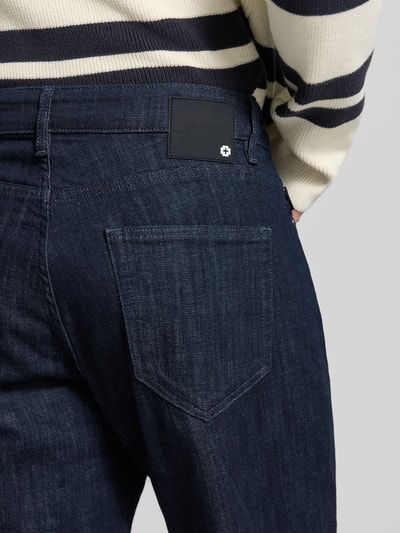 Männermodel trägt Relaxed Fit Jeans aus Baumwoll-Mix Modell 'Tan' von Strellson in dunklem Blau, raue Textur, Nahaufnahme Rückansicht, Herren Relaxed Fit Jeans von Strellson.