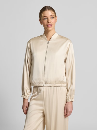 Modelka kobieta nosi Blouson mit Stehkragen und Reißverschluss od comma, jasny beż, materiałowy miks z wiskozą, krój regular fit, długość tyłu w rozmiarze 36: 52 cm, szerokość w rozmiarze 36: 50 cm, długość rękawa w rozmiarze 36: 57 cm, gładka tekstura, widok całej sylwetki z przodu.