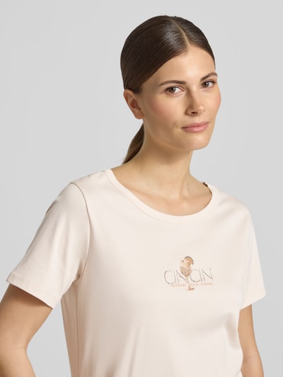Frauenmodel trägt T-Shirt mit Motiv-Print und Strasssteinbesatz von monari in Beige, Reine Baumwolle, Gerader-Schnitt, Rundhalsausschnitt, Nahaufnahme Oberkörper.