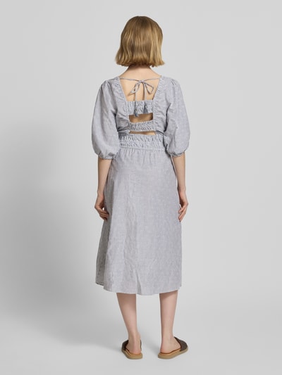 Vrouwenmodel draagt Tailliertes Freizeitkleid aus reiner Baumwolle Modell 'CHIA' van Pepe Jeans in blauw-wit allover-motief, midi-lengte, boothals, pofmouwen met elastische zoom, rechte zoom, zijzakken, getailleerde fit, katoen; volledige lichaamsweergave achteraan.